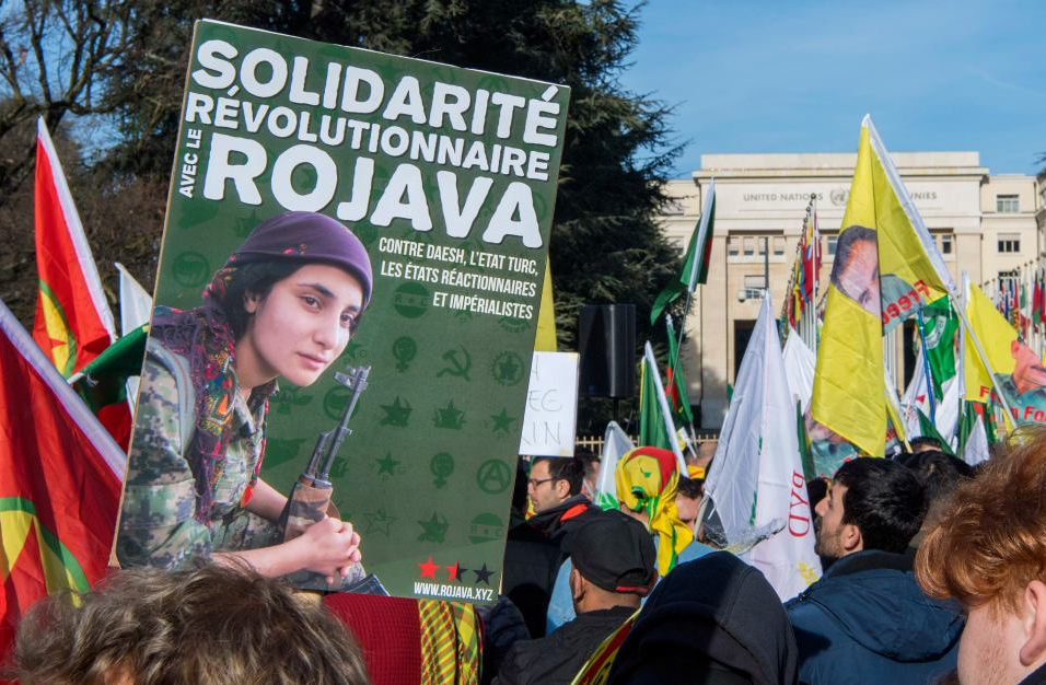 Zdjęcie z demonstracji. Plakat z kurdyjką z karabinem